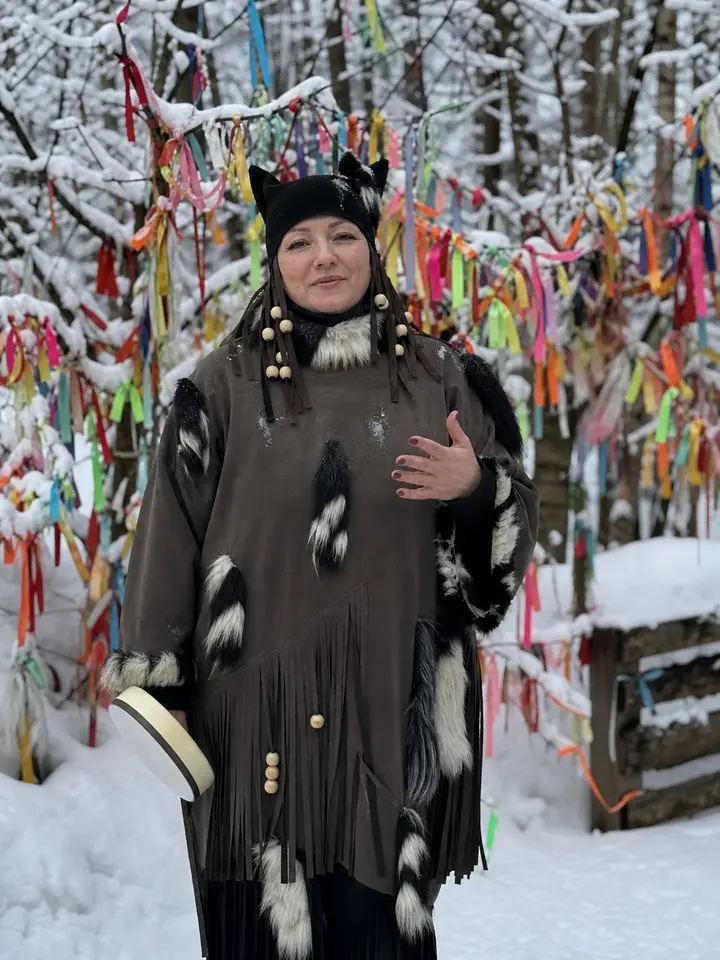 Гость в саамской одежде у дерева с разноцветными лентами